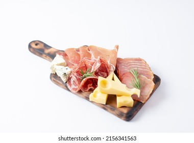 Appetizers table with different antipasti, charcuterie, snacks and cheese. Buffet party. Wooden cutting board isolated on white background, top view
