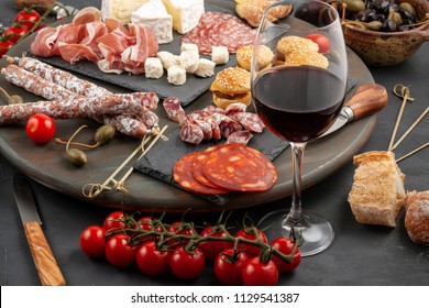 Appetizers table with differents antipasti, cheese, charcuterie, snacks and wine. Mini burgers, sausage, ham, tapas, olives, cheese and baguette over grey concrete background. Top view, flat lay - Powered by Shutterstock