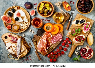 Appetizers table with italian antipasti snacks and wine in glasses. Brushetta or authentic traditional spanish tapas set, cheese variety board over grey concrete background. Top view, flat lay - Shutterstock ID 754215313
