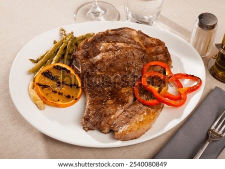 Appetizing beef steak served with grilled orange and bell pepper and boiled asparagus