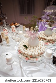 An Appetizing Candy Bar For Holiday Guests Stands On A Table With A White Tablecloth, With Sweets, Candles And Various Utensils, In The Banquet Room.