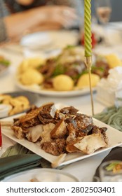 Appetizing close-up of a generous portion of roasted meat with bones served with creamy mashed potatoes on a white plate