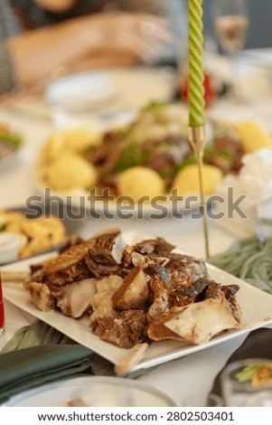 Appetizing close-up of a generous portion of roasted meat with bones served with creamy mashed potatoes on a white plate