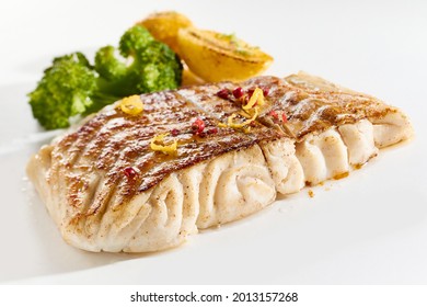 Appetizing composition of yummy fried pollack fish steak and roasted vegetables arranged on white surface