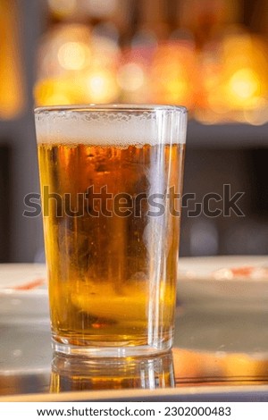 An appetizing and fresh draft beer served in a glass on the table of a bar terrace, Summer