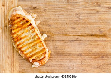 Appetizing grilled Italian panini bread cheese sandwich with melting cheese on a bamboo cutting board with copy space, overhead view