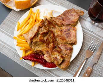 Appetizing grilled pork escalope with side dish of fried potatoes and baked pepper served with cream cheese dip..