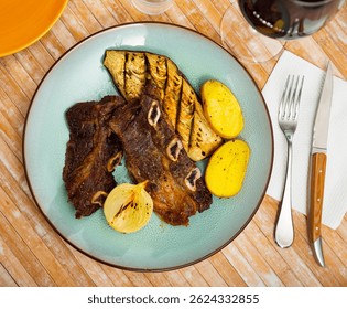 Appetizing grilled veal steak with baked eggplant and fried potatoes