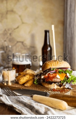 Appetizing hamburger on a wooden board, accompanied by crispy fries and refreshing beer, delicious and tempting appearance, vertical shot