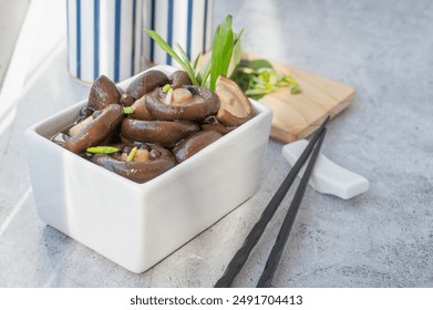 Appetizing marinated shiitake mushrooms in a white salad bowl on a wooden table... marinated shiitake mushrooms, ready to eat. - Powered by Shutterstock