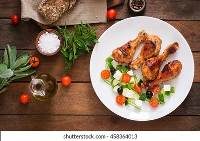 Appetizing Oven Baked Golden Chicken Drumsticks And Greek Salad. Top View