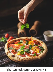 Appetizing pizza with tomatoes and cheese on a dark wooden background. Slice of pizza with stretchy cheese - Shutterstock ID 2165298445