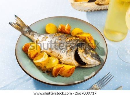 Appetizing roasted dorada served on plate with baked potatoes. Healthy eating