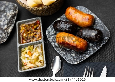 Appetizing sausages of Uruguayan cuisine Chorizo Criollo, grilled and served with two types of pickled salads
