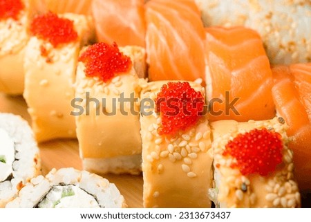 Appetizing set of rolls with cheese, salmon, tobiko calve, white sesame, Philadelphia cheese on wooden serving board. Front view