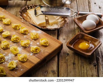 Appetizing Small Handmade Dumplings On A Floured Wooden Cutting Board On A Wooden Background. Kitchen Utensils, Ingredients. Restaurant And Home Cooking. There Are No People In The Photo.