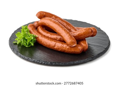 An appetizing stack of plump, golden brown smoked sausages, richly colored and speckled, accompanied by fresh vibrant green lettuce leaves on a dark textured slate serving board, isolated on white background