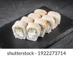 appetizing sushi roll with philadelphia cucumber cheese and escolar on a black stone plate.