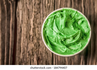 Appetizing Tub Of Green Italian Ice Cream For A Delicious Refreshing Snack On A Summer Day Served On An Old Wooden Able With Copyspace, View From Above