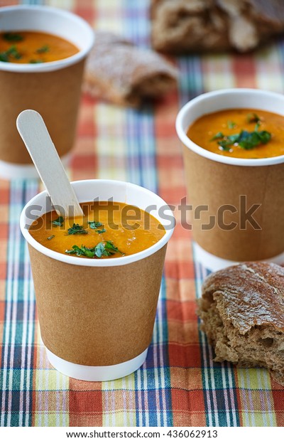 appetizing vegetable creme soup in paper cups\
in the checked\
background