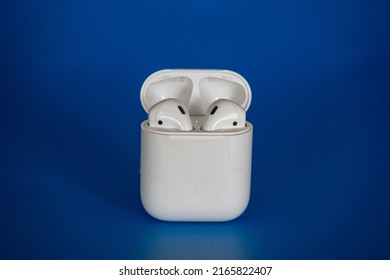 Apple airpods 2 wireless bluetooth headphones in an open white case on a blue background.
