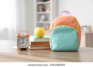 Apple, alarm clock, books and schoolbag on desk in classroom. Back to school concept - Powered by Shutterstock