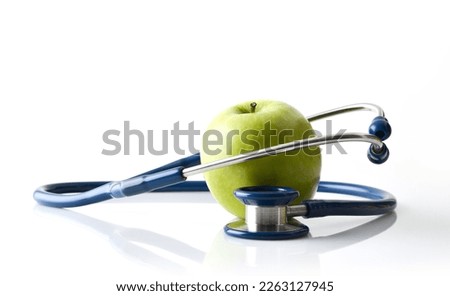 Apple background representing health and stethoscope around reflected on white table and white isolated background. Front view.