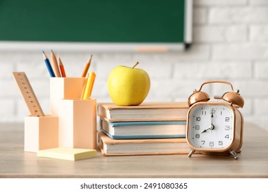 Apple, books, alarm clock and stationery on teacher's desk in classroom. Back to school concept - Powered by Shutterstock