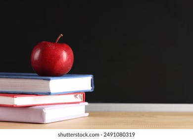 Apple and books on desk near chalkboard. Back to school concept - Powered by Shutterstock