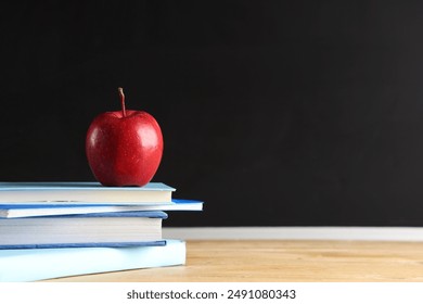 Apple and books on desk near chalkboard. Back to school concept - Powered by Shutterstock