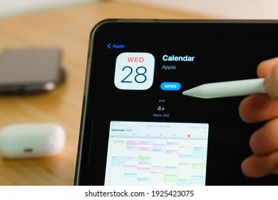 Apple Calendar logo shown by apple pencil on the iPad Pro tablet screen. Man using application on the tablet. December 2020, San Francisco, USA.