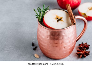 Apple Cider Moscow Mule Cocktail With Cinnamon Stick And Rosemary In Copper On Gray Concrete Stone Background