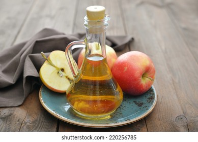 Apple cider vinegar in glass bottle and  fresh apples on wooden background