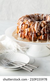 An apple cinnamon pull apart bread on a pedestal stand with dishes for serving.