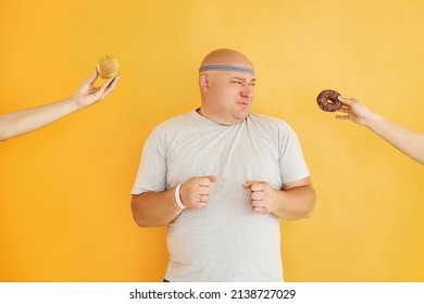 Apple or cookie. Funny overweight man in sportive head tie is against yellow background.