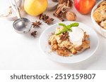  Apple Crumble Dessert, crisp cobbler with Ice Cream, crumble pie with crunchy dough topping in baking dish and plate, with ice cream scoop on white kitchen table