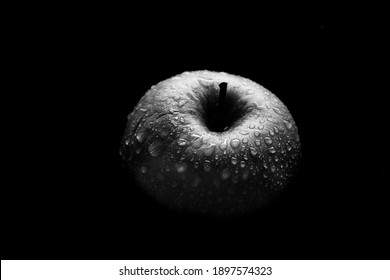 An apple in the dark, an apple in a drop of water in black and white.