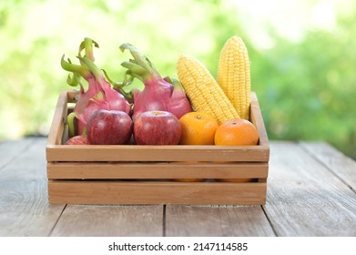 Apple And Dragon Fruit Are Placed On The Left, Oranges And Corn Are Yellow   Placed On The Right Side Of A Wooden Box With A Blurred Green Background. Red : Contain Lycopene, Yellow : Carotenoids.