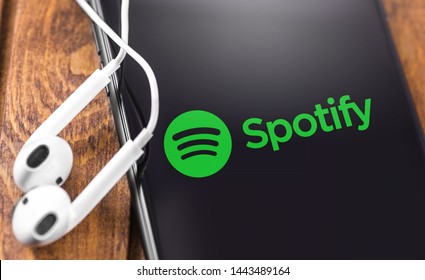 Apple Earpods and iPhone with Spotify logo on the screen. Spotify - online streaming audio service. Moscow, Russia - July 05, 2019
