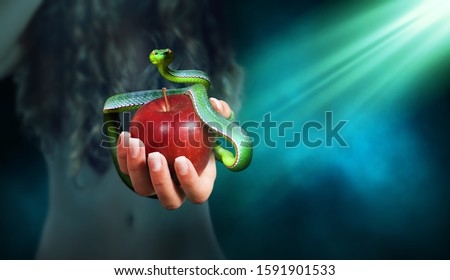 Apple fruit in a hand of a woman with a snake on top of it. Forbidden fruit concept.