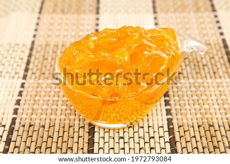 Apple jam in a glass dish on a bamboo mat.