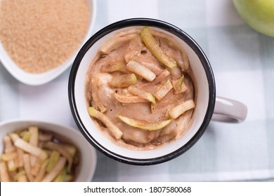 Apple Mug Cake With Ingredients And Sliced Apple On Top Over Wood