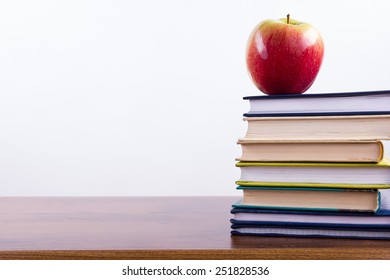 An apple on a stack of colorful books and chalk. Back to school.