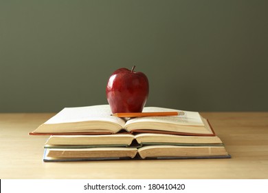 apple on stack of open books with pencil  - Powered by Shutterstock