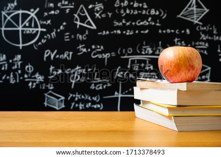 Apple on the stacking of book in front of blackboard with many Mathematical formula. Education background concept.