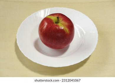 An apple on a white plate. - Shutterstock ID 2312041067