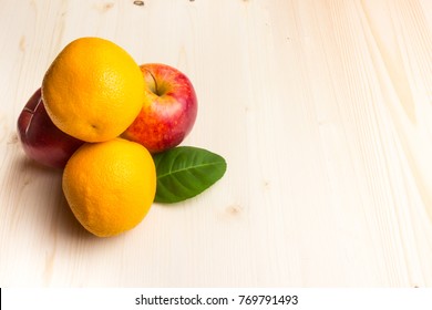 Apple and orange on a wooden board