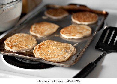 Apple pancakes cooking on the hot stove griddle.  Shallow depth of field.