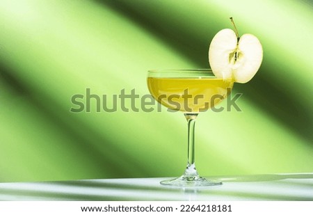 Apple pie alcoholic cocktail beverage with vodka, apple liqueur, cinnamon syrup.. Light green background, hard light, shadow pattern. Minimalistic style