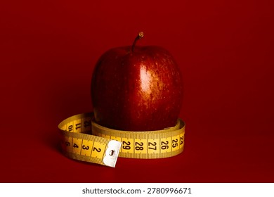 An apple is placed on a red surface with measuring tape wrapped around it for nutrition discussion.